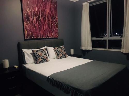 a bedroom with a bed with a painting on the wall at The Perfect Host @ Curtis Apartments in Gladstone