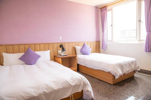 2 Betten in einem Zimmer mit lila Wänden in der Unterkunft Holiday Hotel in Insel Nangan