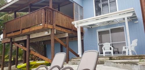 a blue house with a deck and chairs on the patio at Arapati Holiday Homes in Rarotonga