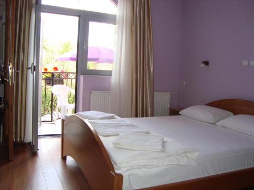 a bedroom with a bed with white sheets and a balcony at Vila Madams - Palić-Serbia in Palić