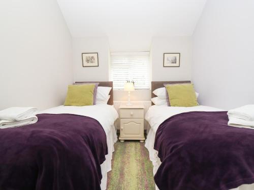 2 camas en una habitación con sábanas moradas y verdes en Peewit Barn, en Moreton-in-Marsh