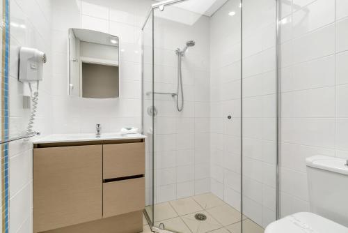 un bagno con doccia, lavandino e WC di Korora Bay Village Resort a Coffs Harbour