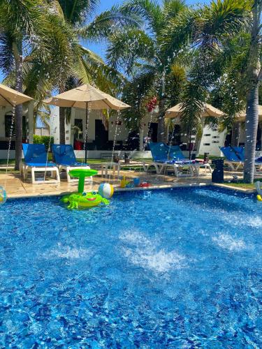 a swimming pool with blue chairs and palm trees at Hotel El Faro in Monterrico
