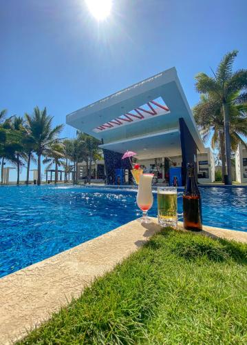 a pool with two glasses of wine next to a building at Hotel El Faro in Monterrico