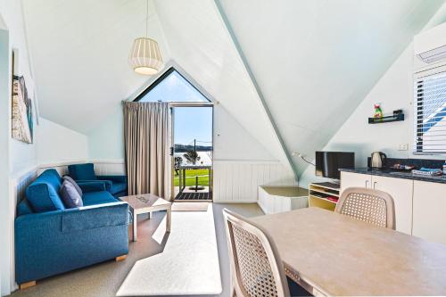 a living room with a blue couch and a table at Beach Cabins Merimbula in Merimbula