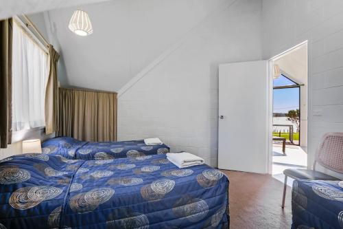 a bedroom with two beds and a balcony at Beach Cabins Merimbula in Merimbula