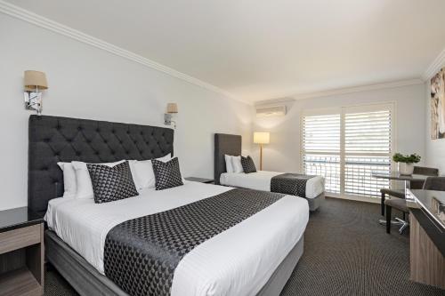 a hotel room with two beds and a television at Lincoln Downs Resort Batemans Bay in Batemans Bay