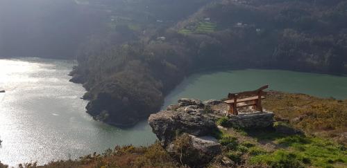 a bench on a cliff next to a body of water at Mirador del Navia in Serandinas