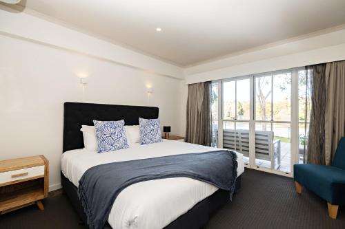 a bedroom with a bed and a large window at Lincoln Downs Resort Batemans Bay in Batemans Bay