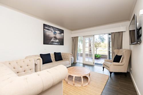 a living room with a white couch and a table at Lincoln Downs Resort Batemans Bay in Batemans Bay