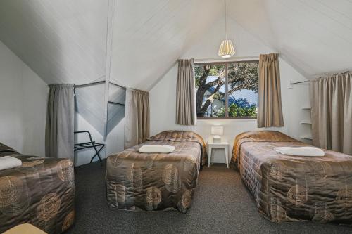 a room with two beds and a window in it at Beach Cabins Merimbula in Merimbula