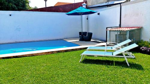 a chair and an umbrella next to a pool at Casa Luna con alberca para 26 personas Cuernavaca in Cuernavaca