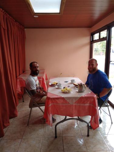 tres hombres sentados en una mesa en una habitación en Hotel La Puesta Del Sol B&B, en Monteverde