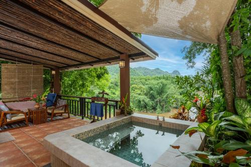 an outdoor pool with a view of the mountains at Home Phutoey River Kwai Hotspring & Nature Resort - SHA Extra Plus in Sai Yok
