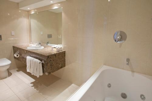 a bathroom with a tub and a sink and a toilet at Copthorne Hotel Palmerston North in Palmerston North