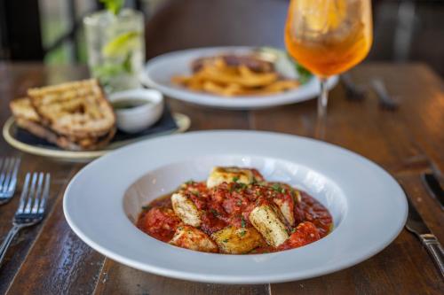 a table with two plates of food and a glass of beer at Lincoln Downs Resort Batemans Bay in Batemans Bay