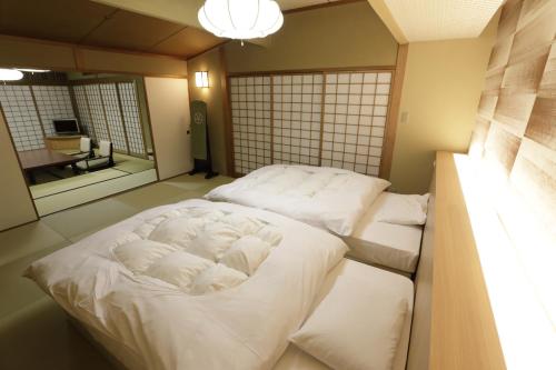a large white bed in a room with a mirror at Oku Yugawara SANSUIROU in Yugawara