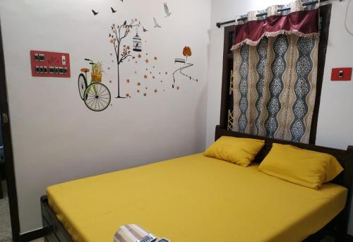 a bedroom with a bed with yellow sheets and birds on the wall at BlueMoon Homestay in Puducherry