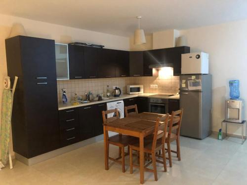 a kitchen with black cabinets and a table and chairs at Tranquil Country Condo - Tersefanou in Larnaca