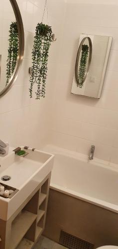 a bathroom with a white tub and a sink and a mirror at Cityclose for five Malmö in Malmö