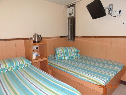 um quarto com duas camas e uma televisão na parede em Fortune Hotel em Hong Kong