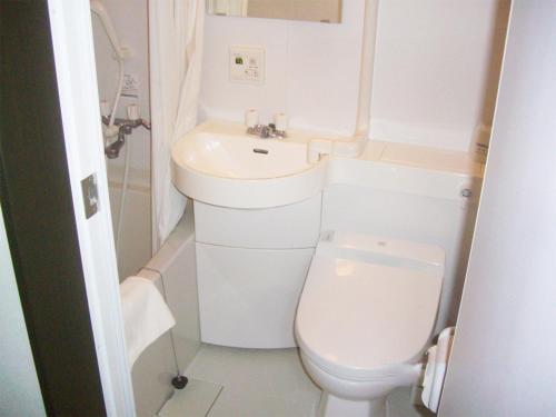 a small bathroom with a toilet and a sink at Tama Hotel in Ishinomaki