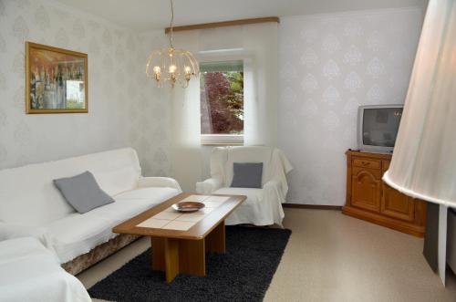 a living room with a white couch and a table at 3 Sterne Ferienwohnungen Wachter in Bischofsgrün
