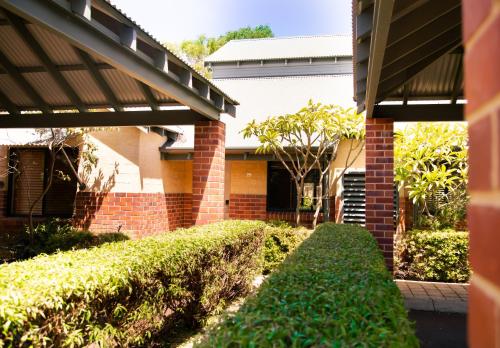 a brick house with a hedge in front of it at Presidential Bungalow in Busselton