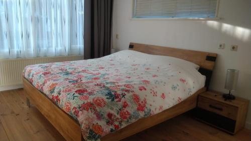 a bedroom with a bed with a floral comforter at B&B - Make a Wisch in Silvolde