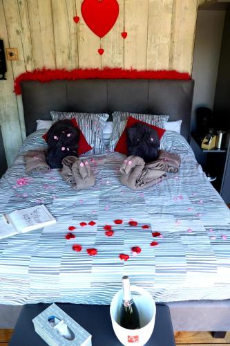 a bed with red rose petals on it at La chambre du puits avec 2 jacuzzis , sauna et Hammam privatif in Tournai