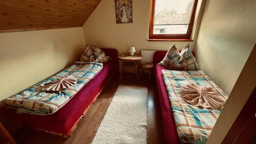 Cette petite chambre comprend deux lits et une table. dans l'établissement Ubytovanie Taraj, à Zuberec