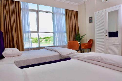 een slaapkamer met 2 bedden en een groot raam bij Sur Inn Hotel Apartments صور ان للشقق الفندقية in Sur