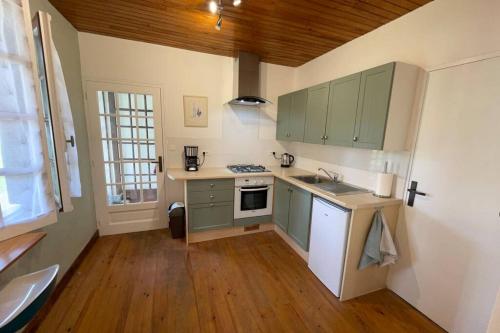 Il comprend une cuisine avec des placards verts et du parquet. dans l'établissement Gite Jeanroy a Cheerful 2 Bedroom Rural Gite, à Saint-Martial-Viveyrol