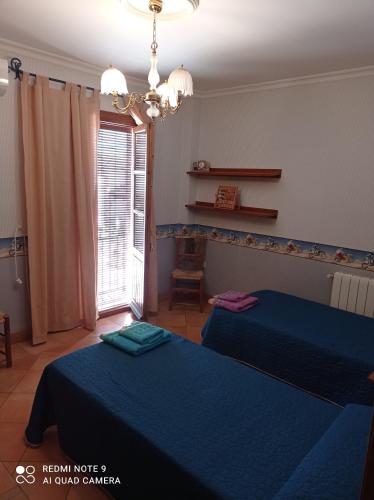 a bedroom with two beds and a window at La Casa del Paseo in Baños de la Encina