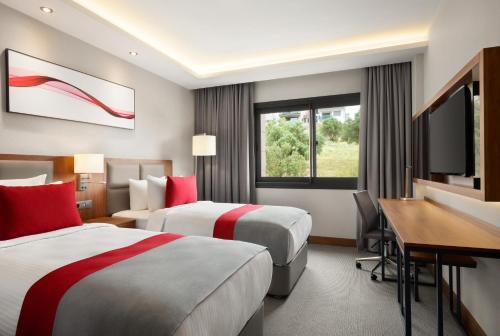 pokój hotelowy z dwoma łóżkami i biurkiem w obiekcie Ramada by Wyndham Izmir Aliaga w mieście Izmir