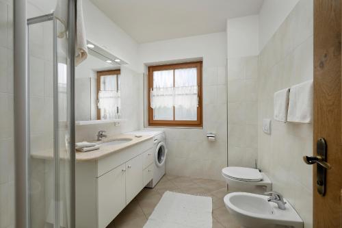 La salle de bains blanche est pourvue d'un lavabo et d'un lave-linge. dans l'établissement Wohnhof, à Lagundo