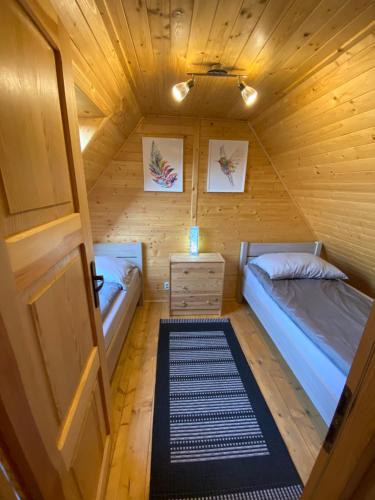 een kamer met twee bedden in een houten hut bij Dolina Bella - całoroczne domki z balią i sauną w sercu Kaszub in Gołubie