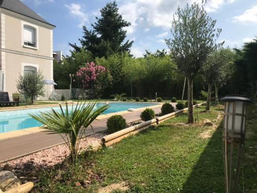 a swimming pool in a yard next to a house at LA VILLA BOLERO in Saint-Cyr-sur-Loire