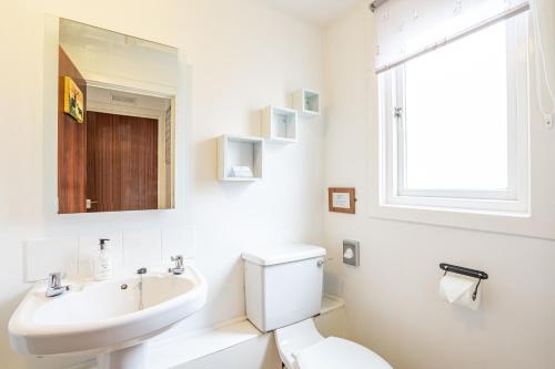 a white bathroom with a sink and a toilet at Heather Lodge 4, sleeping 6 in Belladrum