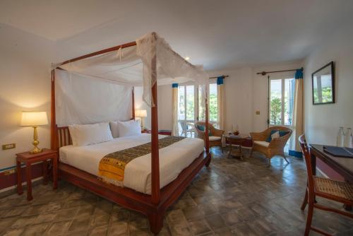 a bedroom with a canopy bed and a desk at The Belle Rive Boutique Hotel in Luang Prabang