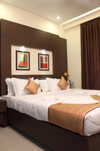 a large bed with white sheets and pillows at Hotel Pristine Residency in Ahmedabad