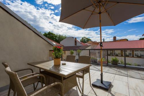 a wooden table with an umbrella on a patio at Luxusní velký apartmán s terasou v centru Litomyšle in Litomyšl