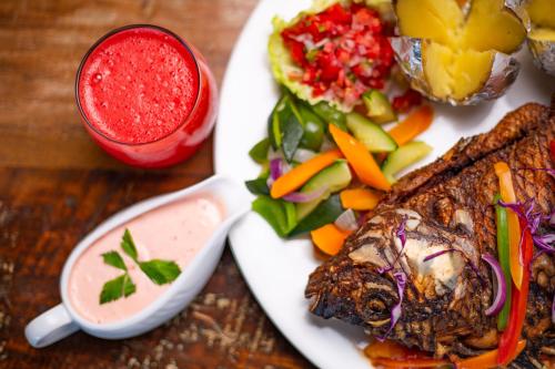 a plate with a steak and a salad and a drink at Humura Resorts in Kampala