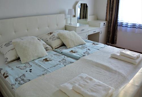 a white bed with towels and pillows on it at Unicum Vendégház in Abádszalók