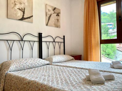 1 dormitorio con 2 camas y ventana en Piso San Andrés - Picos de Europa, en Carreña