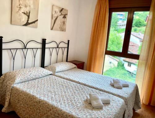 a bedroom with two beds and a large window at Piso San Andrés - Picos de Europa in Carreña de Cabrales 