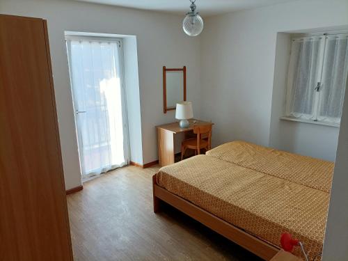 a bedroom with a bed and a table and a window at Appartamenti Alpino in Baselga di Pinè