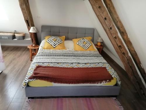 a bed with yellow pillows and a blanket on it at Maison dans le bourg in La Chapelle-Montligeon
