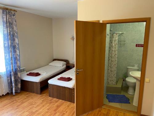 a small bathroom with two beds and a shower at Hotel Fortuna in Taman