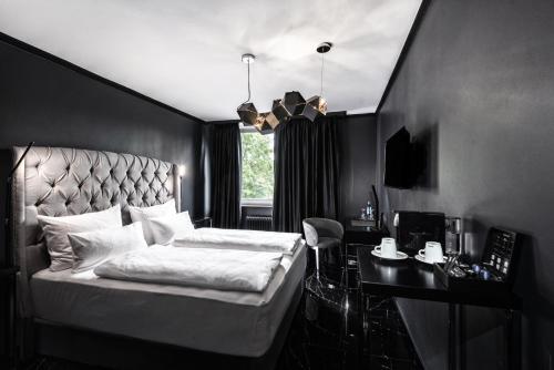 a black bedroom with a bed and a desk and a window at Hotel Belmont Classic in Bonn